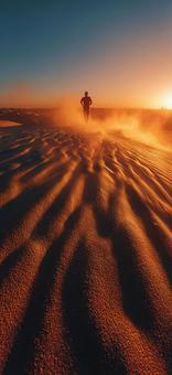 夕日に染まる砂漠でトレーニングする男性 夕日に染まる砂漠でトレーニングする男性の写真