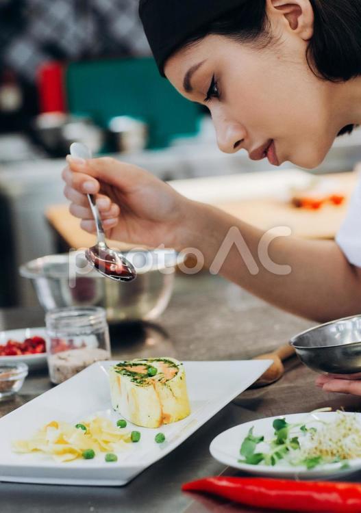 料理を仕上げる女性シェフ キュイジーヌ,キッチン,厨房の写真素材