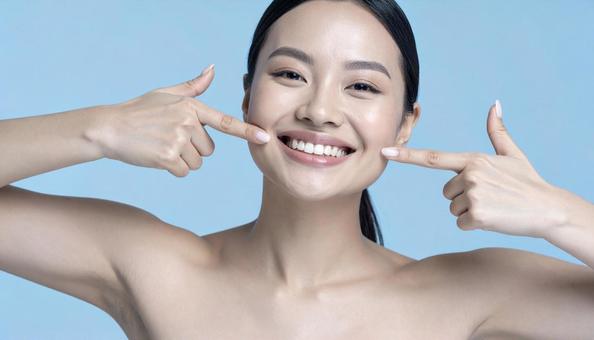 白く健康な歯を指差して笑う女性の写真