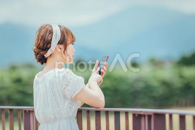 自然の中でスマホを持つ女性 スマホ,携帯電話,アプリの写真素材