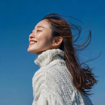 青空を背景に、笑顔を見せる若い女性 青空を背景に、笑顔を見せる若い女性の写真