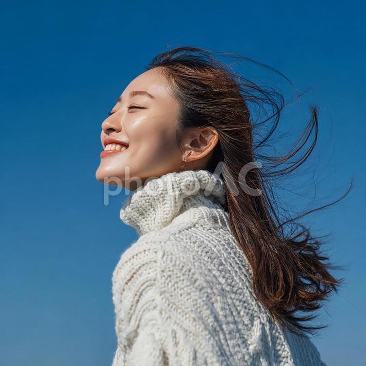 青空を背景に、笑顔を見せる若い女性 女性,若者,大人の写真素材