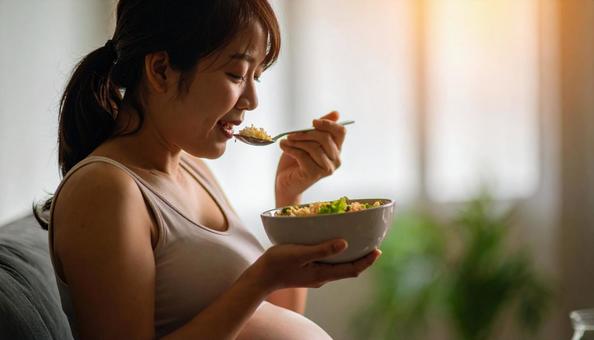 食事を美味しそうに食べる妊婦 食事を美味しそうに食べる妊婦の写真