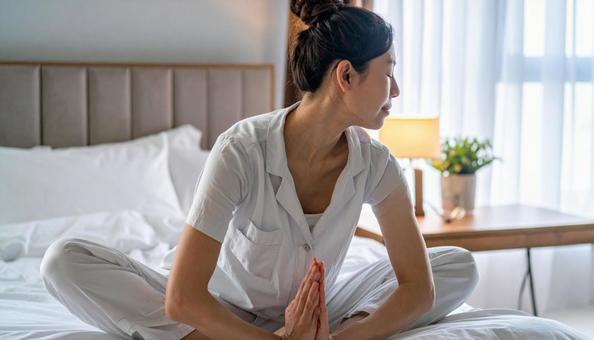 寝る前に寝室でパジャマ姿でヨガをする女性の写真