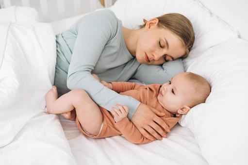 寝かしつけながら眠る女性 添い寝,寝る,ベッドの写真素材