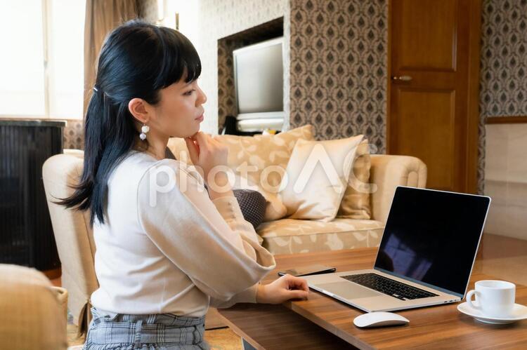 部屋で考えながらパソコンを操作する女性　テレワーク　在宅勤務 女性,テレワーク,リモートワークの写真素材
