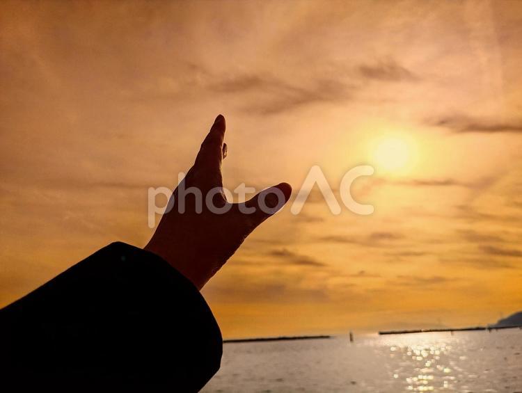 夕日に差し伸べる手 夕日,夕方,海の写真素材