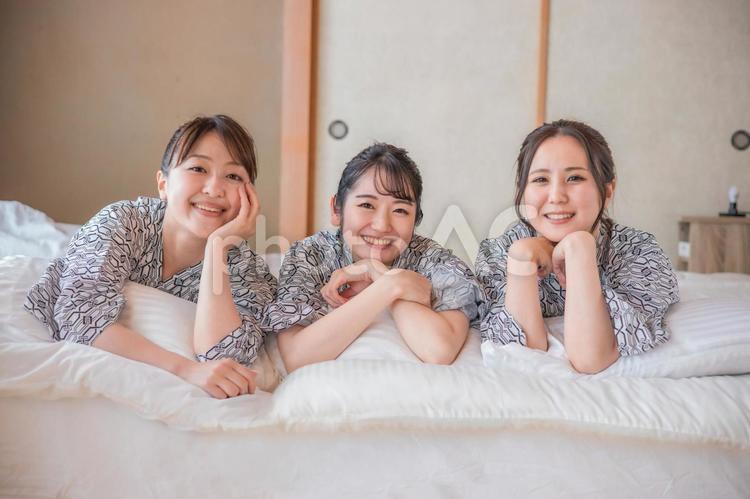 女子旅・布団でくつろぐ女性たち（カメラ目線） 女子旅,宿泊,浴衣の写真素材