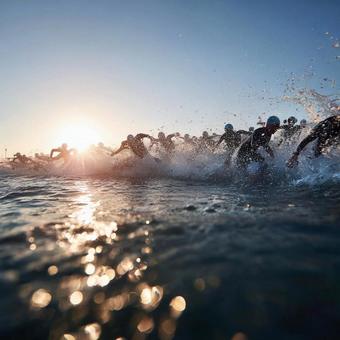 夜明けの海へ走り出すトライアスロン選手 夜明けの海へ走り出すトライアスロン選手の写真