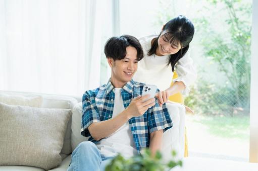 リビングでスマホを見るカップル スマホ,笑顔,カップルの写真素材