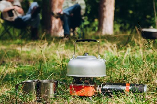 キャンプ用品と人物の足 ケトル,マグカップ,コンロの写真素材