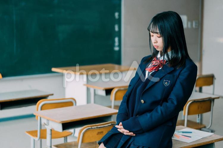 教室の机に腰掛けて暇そうにする女子高生 女子高校生,高校生,学生の写真素材