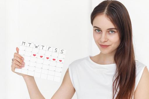 月経期間を示すカレンダーを手に持つカメラ目線の女性 生理,月経,女性の写真素材