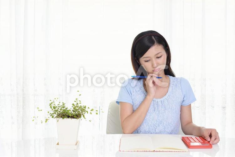 ノートと電卓を使う女性 女性,笑顔,ノートの写真素材