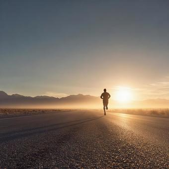 夕焼けに照らされた一本道を走るランナー 夕焼けに照らされた一本道を走るランナーの写真