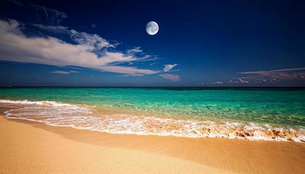ビーチの青空に浮かぶ透けた白い月 ビーチの青空に浮かぶ透けた白い月の写真