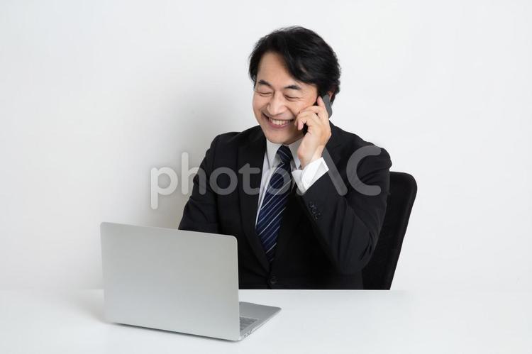 電話をしながら仕事をしている中年のサラリーマン男性 中年,上司,会社員の写真素材