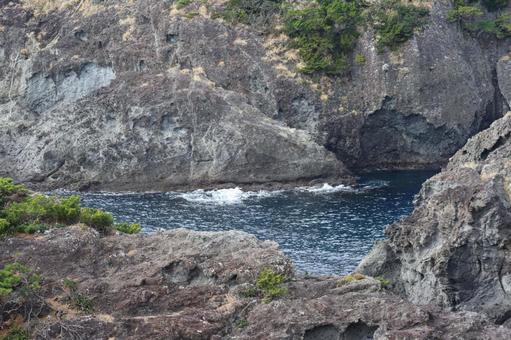 岩壁に囲まれた岩場の青い湾になった海 岩壁に囲まれた岩場の青い湾になった海の写真