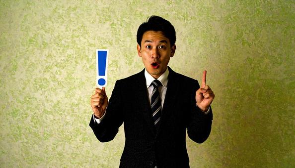 注意!　！を片手に持つ日本人ビジネスマンの写真
