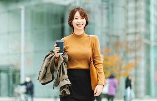 秋のオフィス街を歩く笑顔の女性 女性,人物,秋の写真素材
