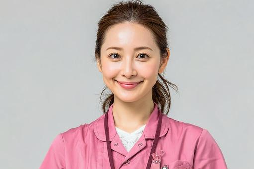 ピンクの制服を着た笑顔の女性介護士 ピンクの制服を着た笑顔の女性介護士 介護士,女性,笑顔の写真素材