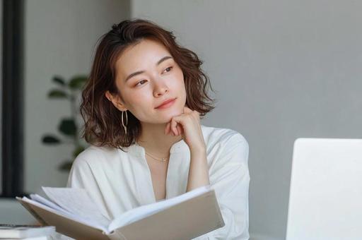 デスクで本を読むビジネス女性の写真