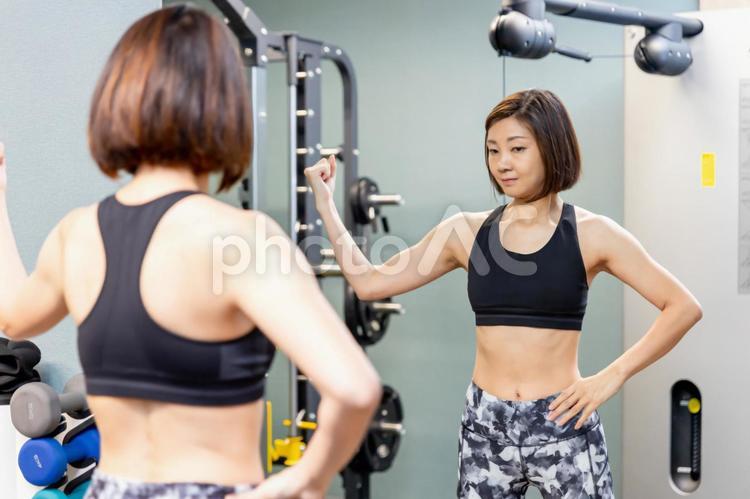 鏡を見てボディメイクする女性（腕） ボディメイク,筋トレ,エクササイズの写真素材