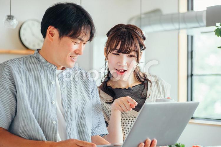 キッチンの前でパソコンを使う男女（笑顔） パソコン,夫婦,ノートパソコンの写真素材