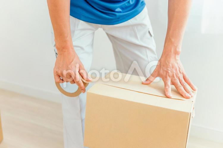 段ボールを持った作業着の男性 ダンボール,段ボール,男性の写真素材