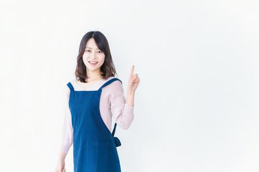 エプロンを着ておすすめを示す若い女性 エプロンを着ておすすめを示す若い女性の写真