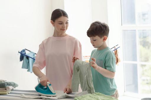 洋服を持っている男の子とアイロンをする女性 洋服を持っている男の子とアイロンをする女性 親子,女性,男の子の写真素材