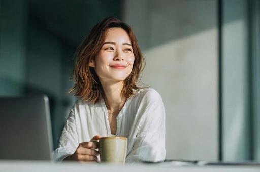 デスクで一息つくビジネス女性 デスクで一息つくビジネス女性の写真