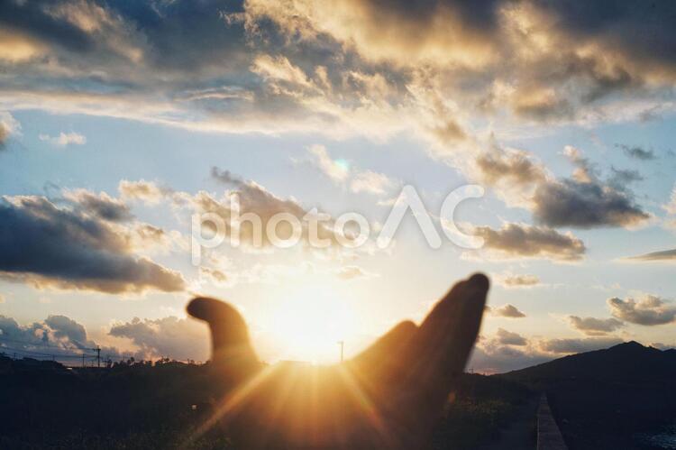手のひらに夕日を乗せる あおぞら,そら,光芒の写真素材