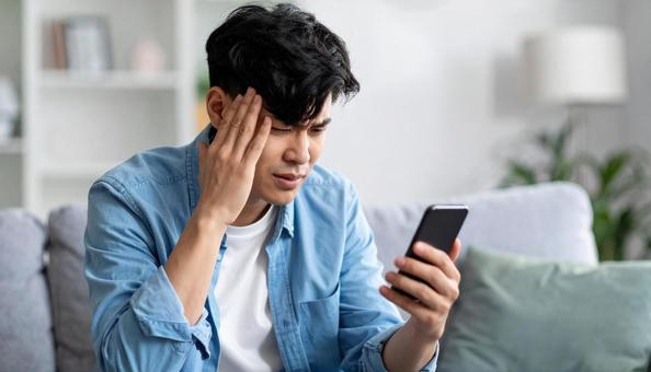 スマホを見てストレスを感じてる表情と仕草 スマホを見てストレスを感じてる表情と仕草の写真
