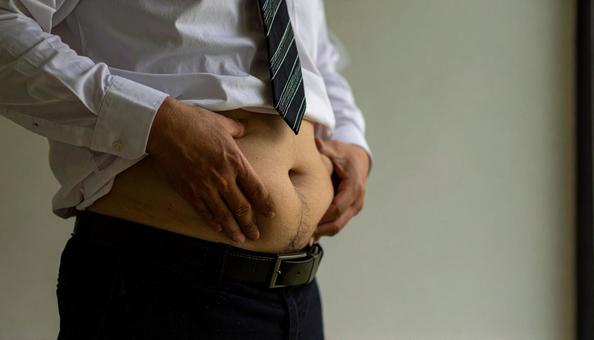 メタボリックなお腹に手を触れる男性 メタボリックなお腹に手を触れる男性の写真