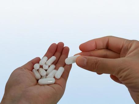 手のひらに載せた大量のカプセル錠をつまむ 薬,カプセル,カプセル錠の写真素材