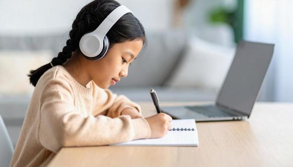 お気に入りの音楽を聴きながら勉強する女性 お気に入りの音楽を聴きながら勉強する女性の写真