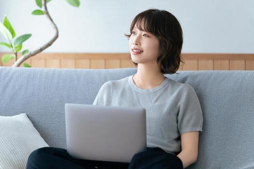 ソファに座ってパソコンを使う女性 女性,ソファ,パソコンの写真素材