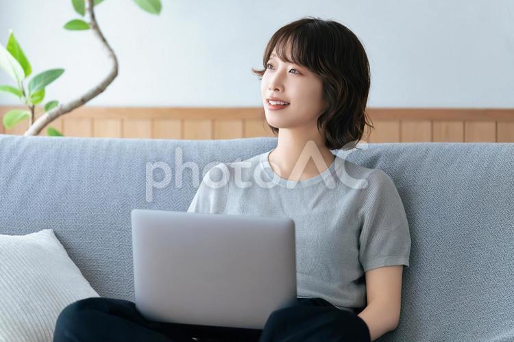 ソファに座ってパソコンを使う女性 女性,ソファ,パソコンの写真素材