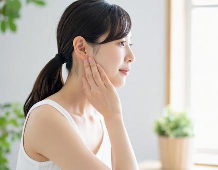 困った顔で手を頬に当てる若い女性 困った顔で手を頬に当てる若い女性の写真