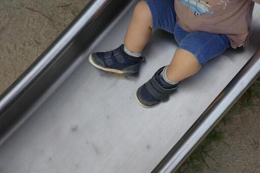 公園の滑り台で座って止まる半ズボンの子供 子供,すべり台,座るの写真素材