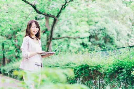 外でパソコンを使う若いビジネスウーマン 外でパソコンを使う若いビジネスウーマン 電波,日本人,野外の写真素材