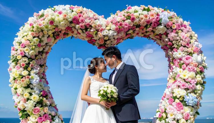 ハート形の花のアーチの前の新郎新婦 ウエディング,アーチ,デコレーションの写真素材