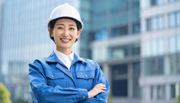 高層ビルの背景に作業服の笑顔の若い女性 高層ビルの背景に作業服の笑顔の若い女性の写真