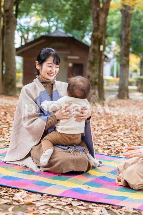 公園で赤ちゃんと抱っこしてママ友と話す女性 親子,母親,主婦の写真素材