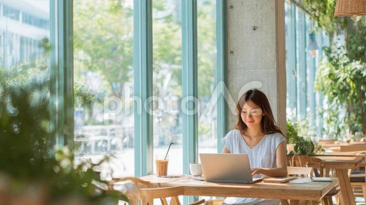 カフェでパソコン作業をする笑顔の女性 カフェ,ノマド,テレワークの写真素材