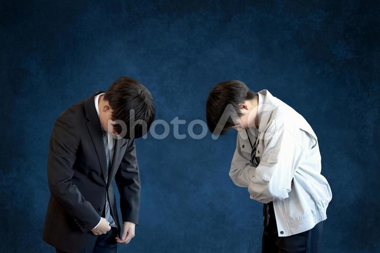 うなだれるビジネスマンたち 謝罪,お詫び,頭を下げるの写真素材