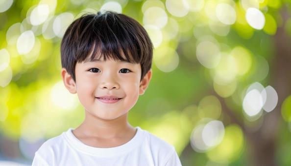 少年のポートレート 緑の背景 木漏れ日 少年のポートレート 緑の背景 木漏れ日の写真