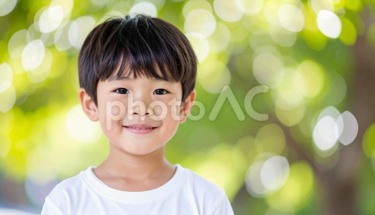 少年のポートレート　緑の背景　木漏れ日 少年,夏,ポートレートの写真素材