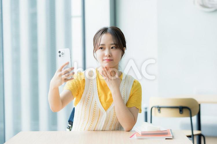 カフェでスマホを見る学生 スマホ,若い女性,笑顔の写真素材